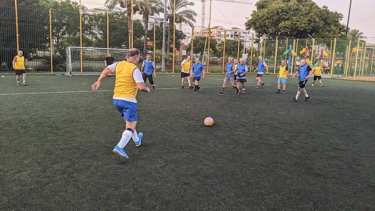 Older players playing walking football on an artificial pitch