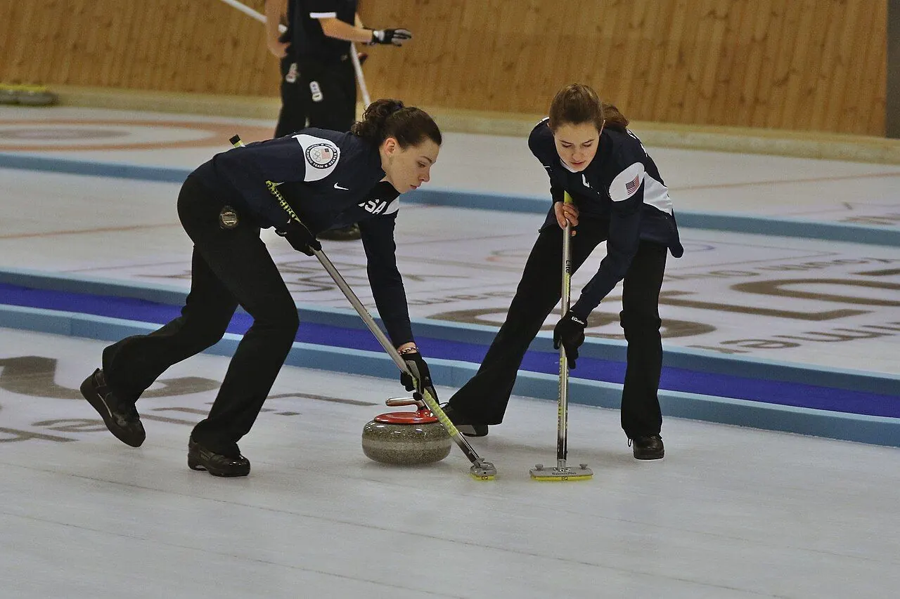 Curler sliding a granite stone along the ice